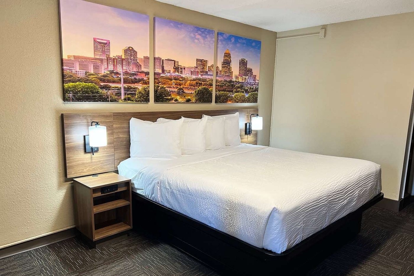 King guest room at Days Inn Monroe — Charlotte skyline triptych artwork above bed